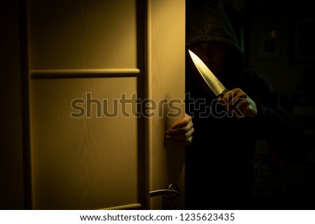 Photo of robber's hands with knife at door