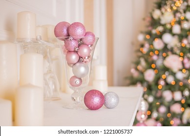 Photo of romantic holiday interior design, traditional Christmas tree, white candles, luxury silver and pink balls as decoration in vase , restaurant decor, hotel decoration. Trendy christmas