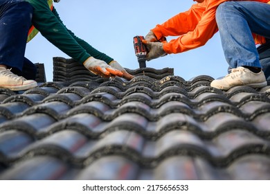 Photo Of A Roofer Working On The Roof Of The House Use A Drill To Drill The Screws To Fix The Cement Tile Roof.