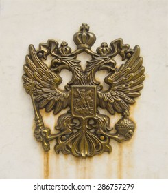 photo of Russian two-headed metal rusty eagle on white stone texture- a symbol of imperial Russia