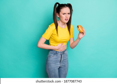 Photo Of Sad Unwell Young Woman Dressed Yellow T-shirt Holding Burger Overeating Arm Hand Stomach Isolated Teal Color Background