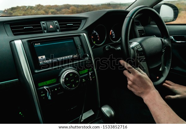 Photo of the salon of the black\
car in which the driver goes holding hands behind the\
wheel
