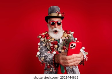 Photo of santa claus funny man amazed hold device dressed christmas tree balls costume sunglasses isolated red color background - Powered by Shutterstock