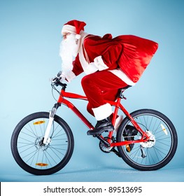 Photo of Santa Claus with red sack riding bike