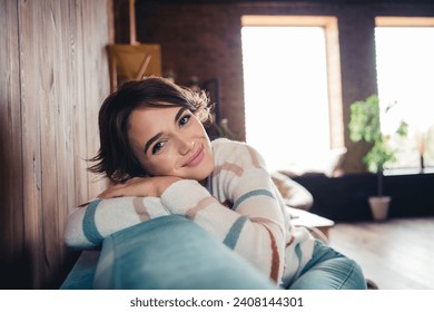 Photo of satisfied adorable girl sitting comfy sofa have good mood pastime morning chill apartment inside