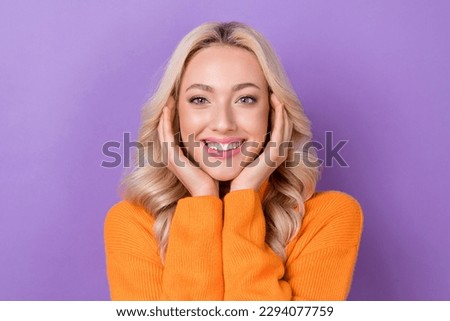 Photo of satisfied glad young person arms touch cheekbones beaming smile isolated on violet color background