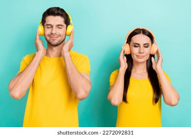 Photo of satisfied good mood two people closed eyes touch wireless headphones chill listen soundtrack melody isolated on aquamarine color background