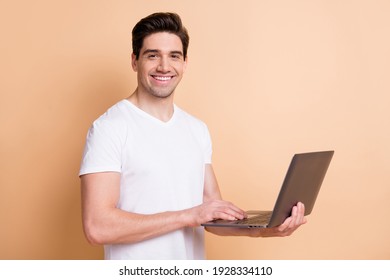 Photo of satisfied young person toothy smile writing text on computer isolated on beige color background