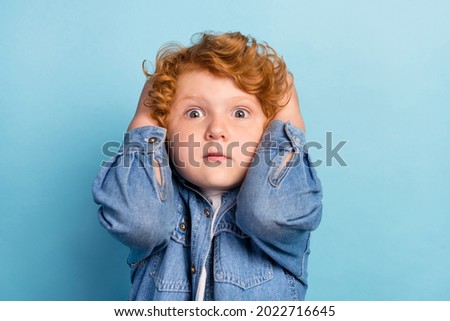 Photo of scared nervous guilty ginger kid touch head speechless wear jeans jacket isolated blue color background