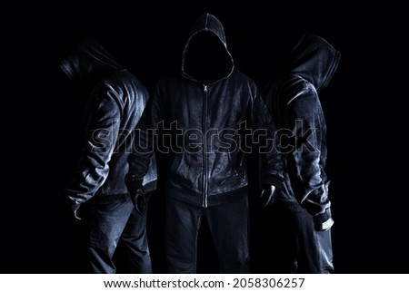 Photo of scary horror stranger stalker men in black hood and clothing on dark and misty background.