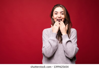 Photo of screaming excited young woman standing isolated over red background. Looking aside.