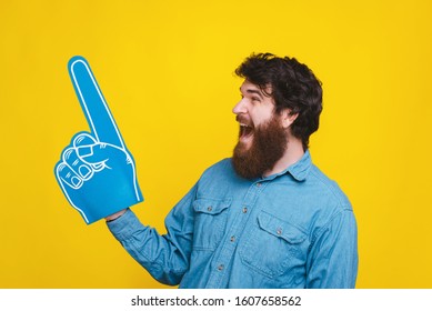 Photo of screaming man pointing away at copyspace with fan foam glove - Powered by Shutterstock