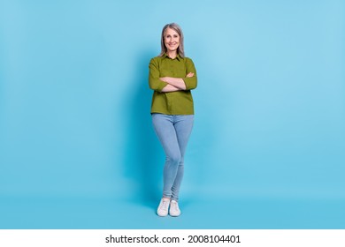 Photo Of Self-assured Grandma Lady Crossed Arms Posing Wear Green Shirt Jeans Footwear Isolated Blue Color Background