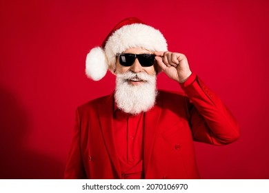 Photo of self-assured successful nice attractive santa claus wear sunglass x-mas headwear suit on red color background