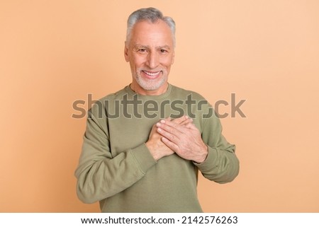 Photo of senior cheerful man arm on heart thankful grateful satisfied peaceful isolated over beige color background