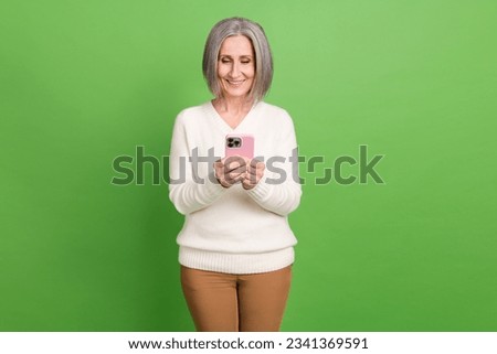 Photo of senior lady grey hair using smartphone wear white pullover writing family group chat viber isolated on green color background