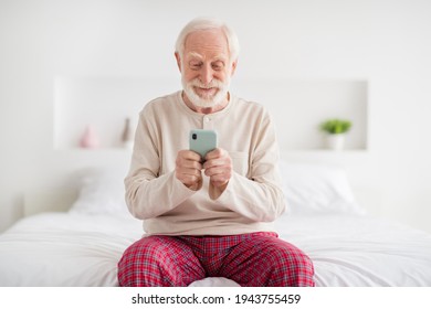 Photo of senior man pensioner happy positive smile sit bed indoors chat type browse internet cellphone - Powered by Shutterstock