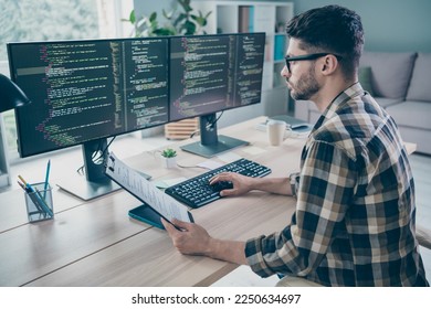 Photo of serious busy coder dressed eyewear holding list typing modern gadget indoors workplace workstation loft