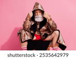 Photo of serious eccentric aged man sit chair put leopard coat hood head isolated on pink color background