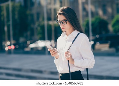 Photo of serious young woman wear white formal shirt spectacles purse typing modern gadget outdoors