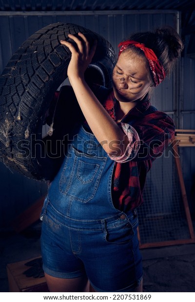 Photo session in a\
car mechanic workshop, young girls dressed in shirts and pants with\
tools from the workshop