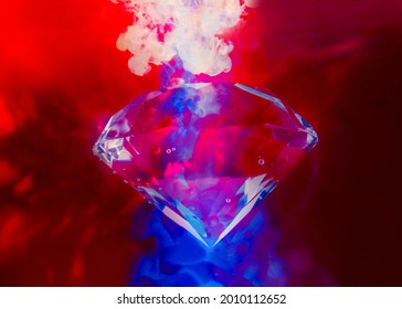 Photo of shining red toned diamond under water with air bubbles and color neon ink splashes.