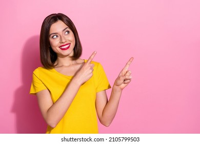 Photo of shiny charming young lady dressed yellow clothes smiling pointing two fingers empty space isolated pink color background - Shutterstock ID 2105799503