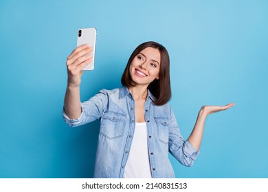 Photo of shiny cute lady dressed denim shirt tacking selfie gadget arm empty space isolated blue color background
