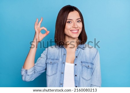 Photo of shiny cute woman wear jeans shirt showing okey sign smiling isolated blue color background