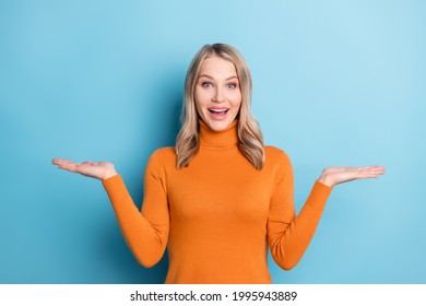 Photo Of Shiny Impressed Young Lady Wear Orange Sweater Compare Two Things Empty Space Smiling Isolated Blue Color Background