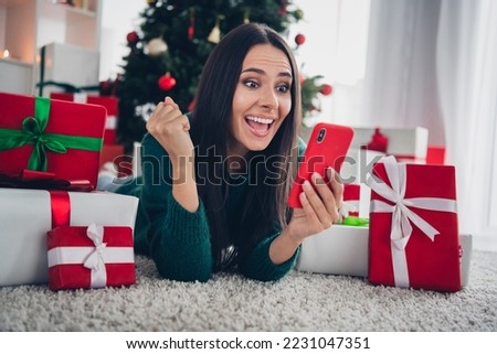 Photo of shiny lucky girl wear xmas green pullover lying floor online sale modern device indoors home room