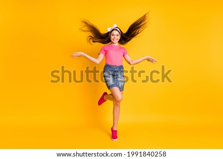 Photo of shiny pretty small schoolgirl dressed pink t-shirt jumping high dancing smiling isolated yellow color background