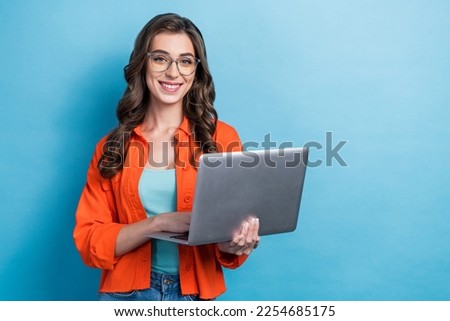 Photo of shiny pretty woman dressed orange jacket spectacles chatting gadget empty space isolated blue color background