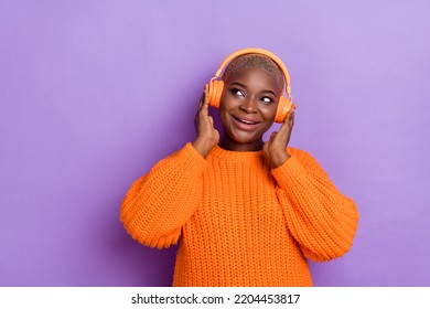 Photo of shiny young lady listen music look empty space dressed trendy autumn orange knitwear sweater isolated on violet color background - Powered by Shutterstock