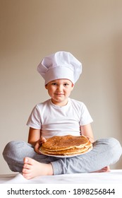 Photo shoot baby in white chef cap with pancakes on a white background . Carnival Festival