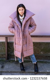 Photo Shoot Of A Beautiful Girl In A Bright Violet Puffy Jacket Or Coat On The Street For A Showroom Show With Stylish Winter Women's Clothing