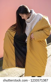 Photo Shoot Of A Beautiful Girl In A Bright Yellow Puffy Jacket Or Coat On The Street For A Showroom Show With Stylish Winter Women's Clothing