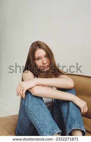 Photo shoot girl model style fashion portrait smile young woman lady white black lifestyle studio shooting beautiful Caucasian happy cute beauty casual sitting jeans posing hands face eyes tenderness
