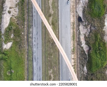 The Photo Showing An Aerial View Of A  Long Modern Conveyor Bridge Structure Crossing The Double Line Road At The Industrial Park Of Sarawak, Malaysia, Southeast Asia.