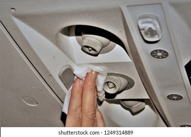 Photo Showing Woman's Hand Cleaning The Air Vents In An Airplane With A White Disinfectant Wipe