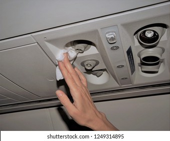 Photo Showing Woman's Hand Cleaning The Air Vents In An Airplane With A White Disinfectant Wipe