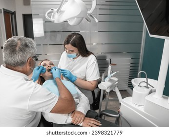 The photo shows how professional teeth cleaning ensures their impeccable cleanliness. A woman at an appointment at a dental center A dentist and his assistant work closely on the condition of the - Powered by Shutterstock