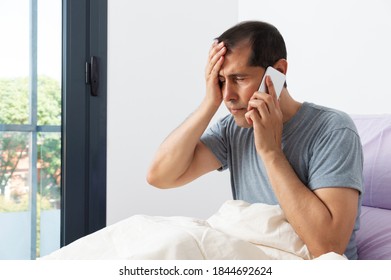 Photo Of Sick And Headache Businessman Sitting On Bed And Calling Doctor In Bedroom