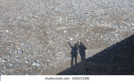 A Photo Of The Silhouettes Of Two People Waving, They Are Standing On The Boat Slipway On Criccieth Beach In Wales UK