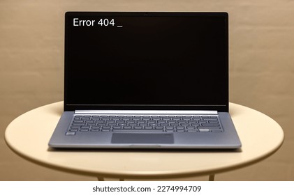 A photo of a silver colored notebook with error message 404 on a black screen. 