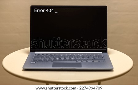 A photo of a silver colored notebook with error message 404 on a black screen. 