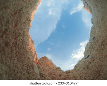 photo of the sky from inside the pink beach sand 