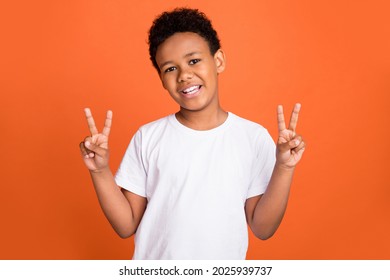 Photo of small cool boy show v-sign wear white t-shirt isolated on orange color background