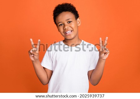 Photo of small cool boy show v-sign wear white t-shirt isolated on orange color background