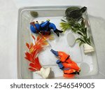 Photo of a small turtle and some aquarium figurines in a clear bowl.